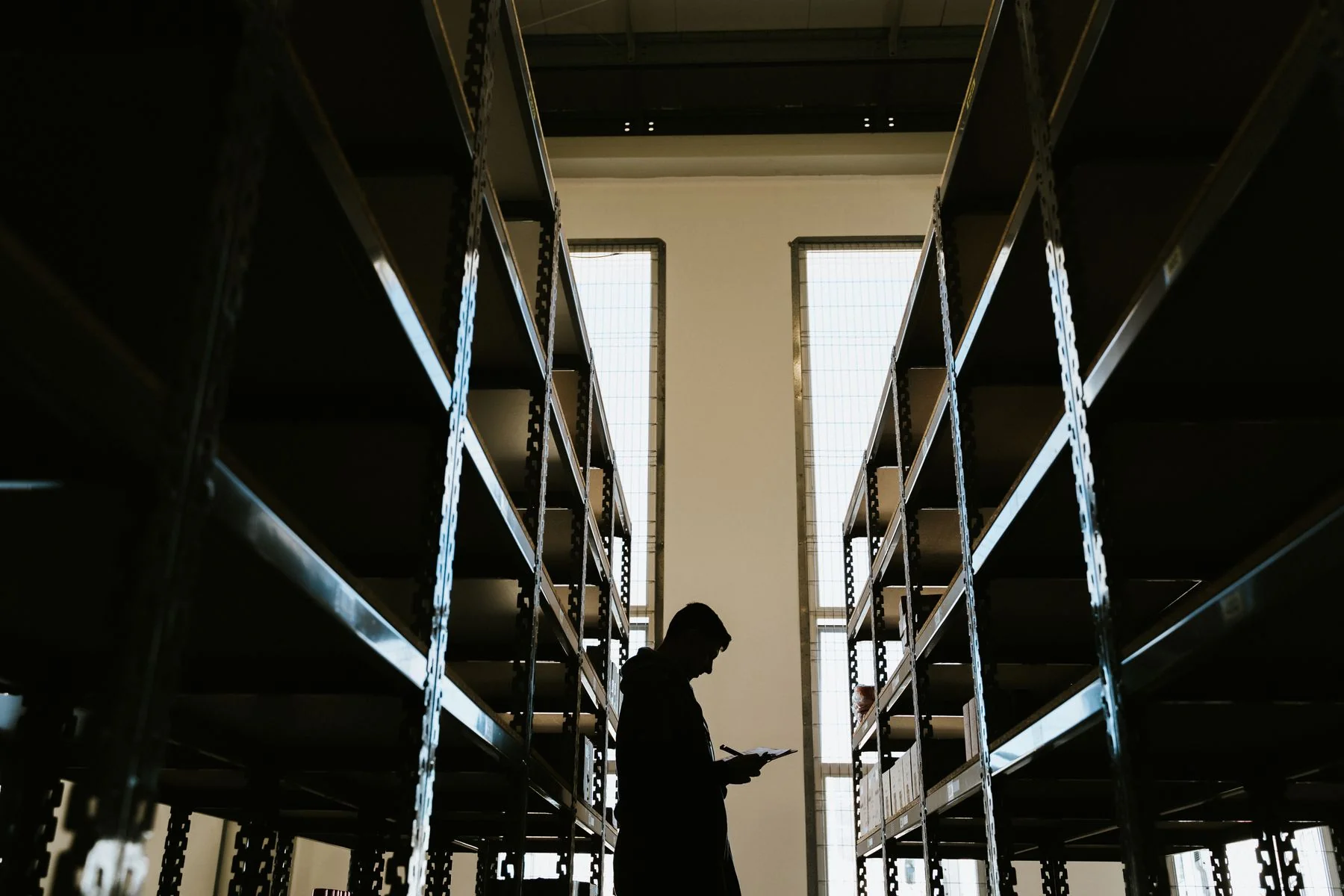 Backlit person with clipboard in a warehouse aisle