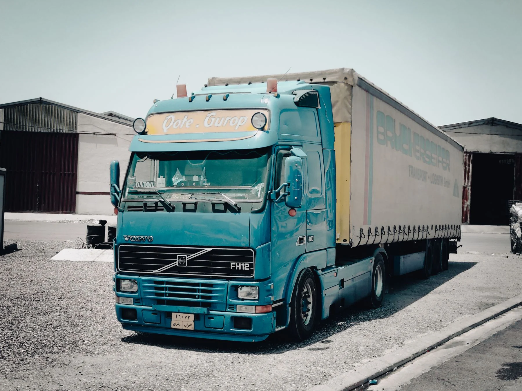 Blue commercial freight truck parked outside warehouse buildings