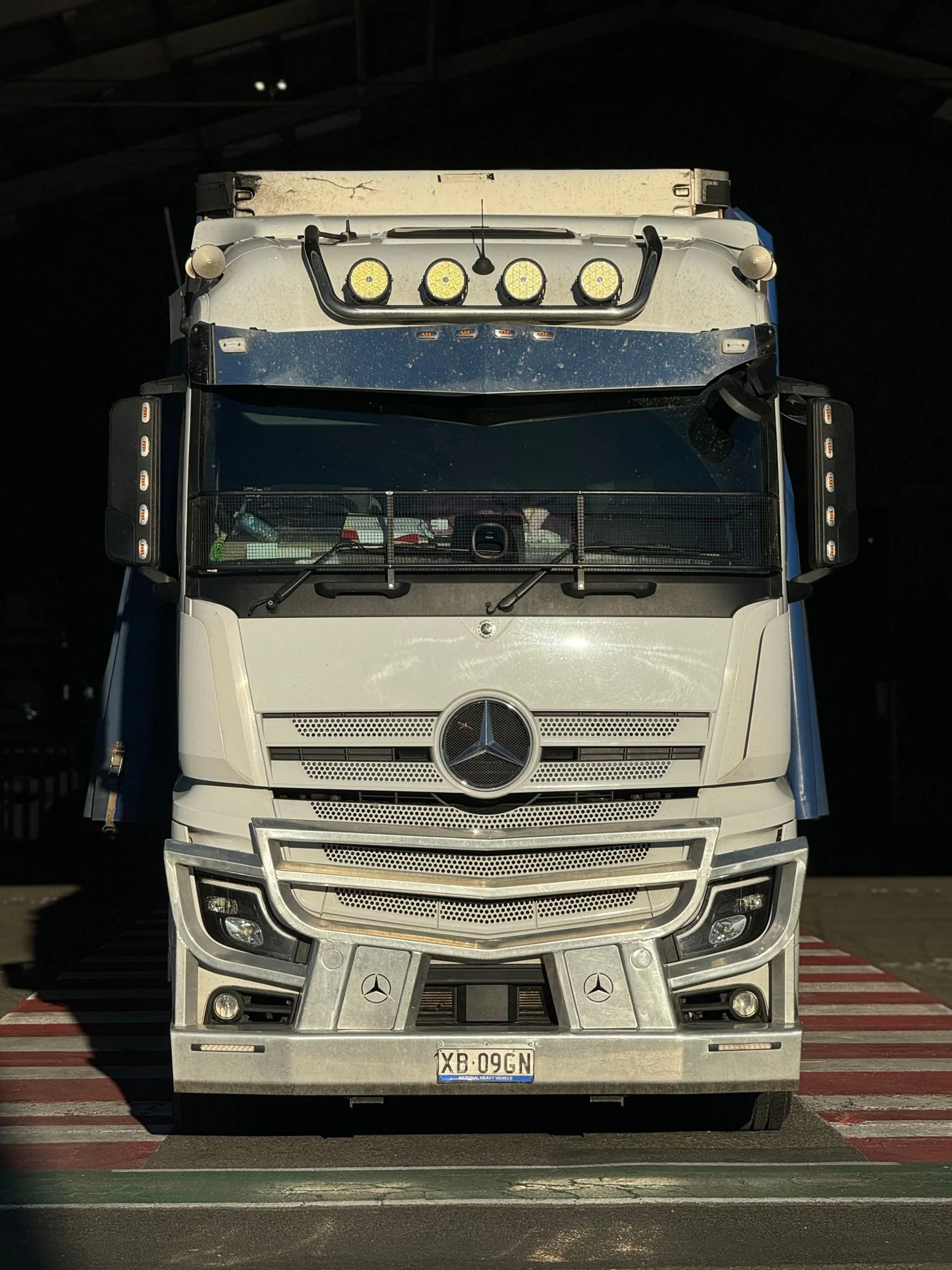 White freight truck parked beside an industrial structure