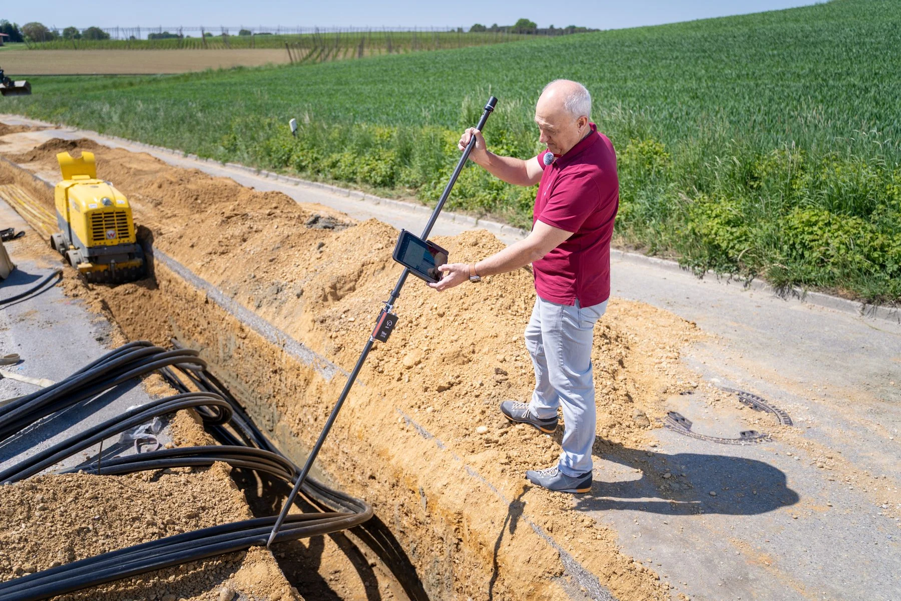 Worker using a surveying instrument beside a utility trench