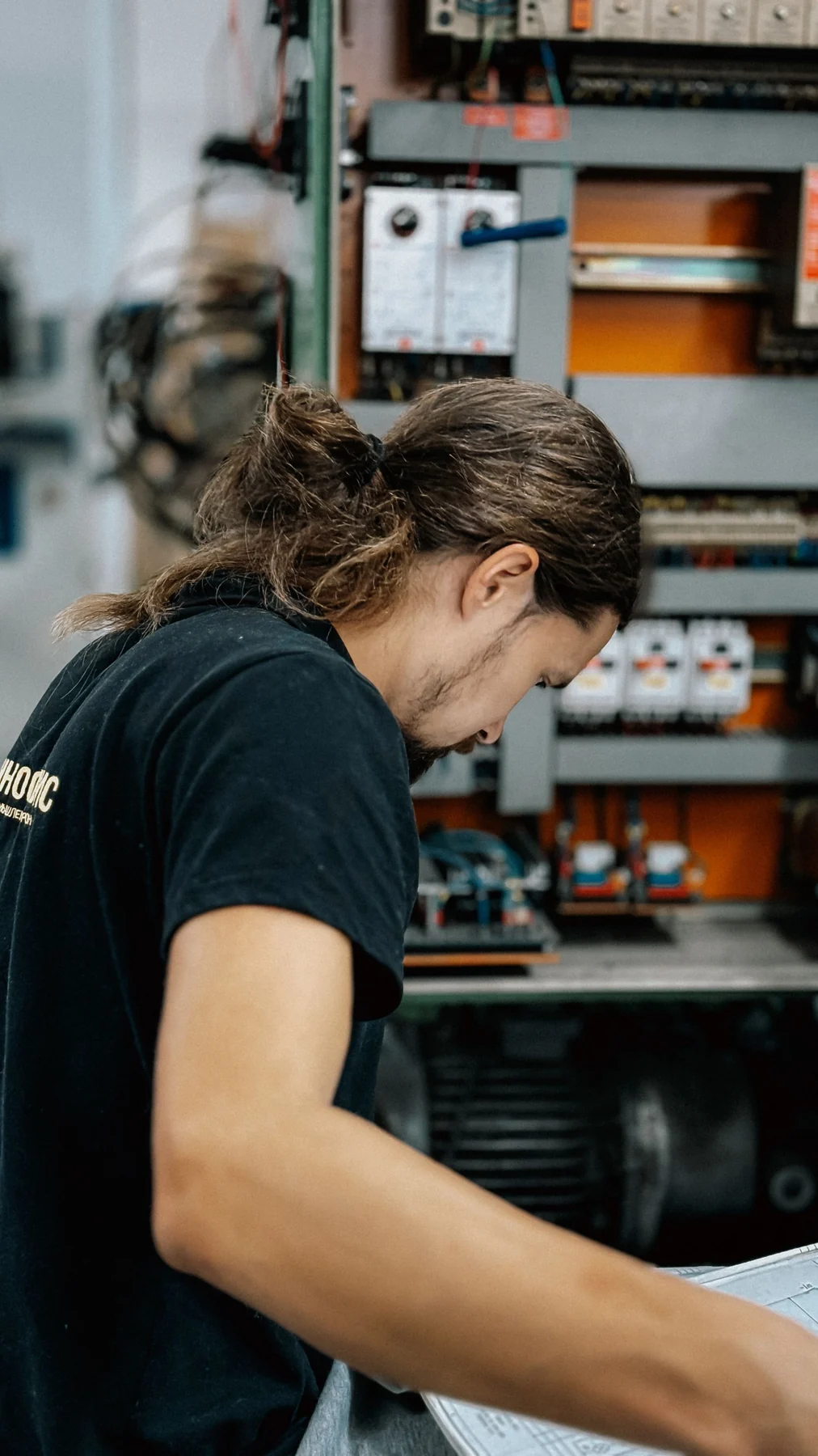 Technician working inside an open industrial electrical panel