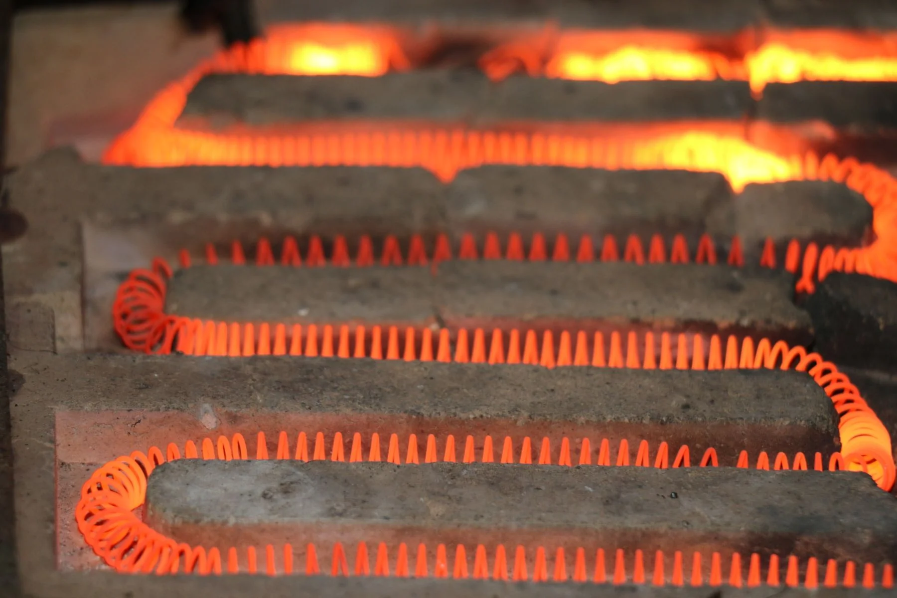 Glowing coiled electrical heating elements on ceramic supports