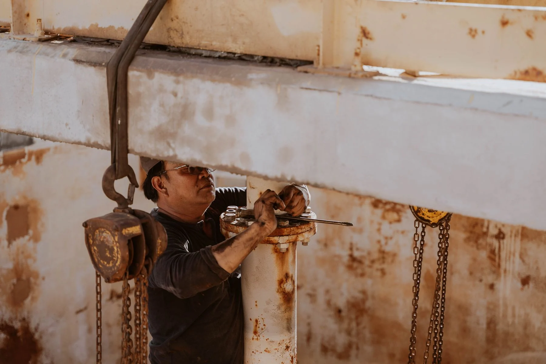 Worker servicing a suspended mechanical assembly inside an industrial structure