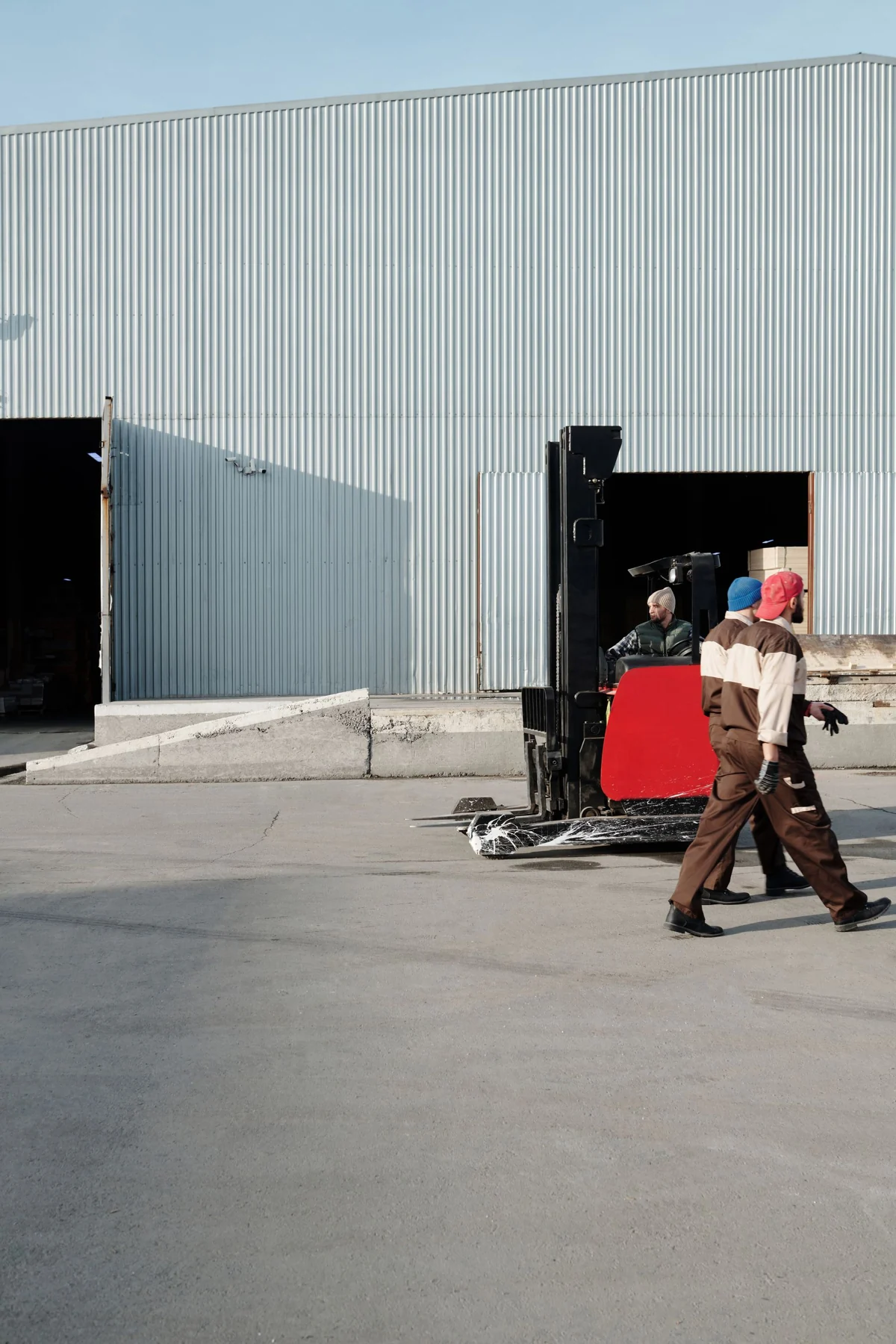 Workers beside a warehouse forklift outdoors