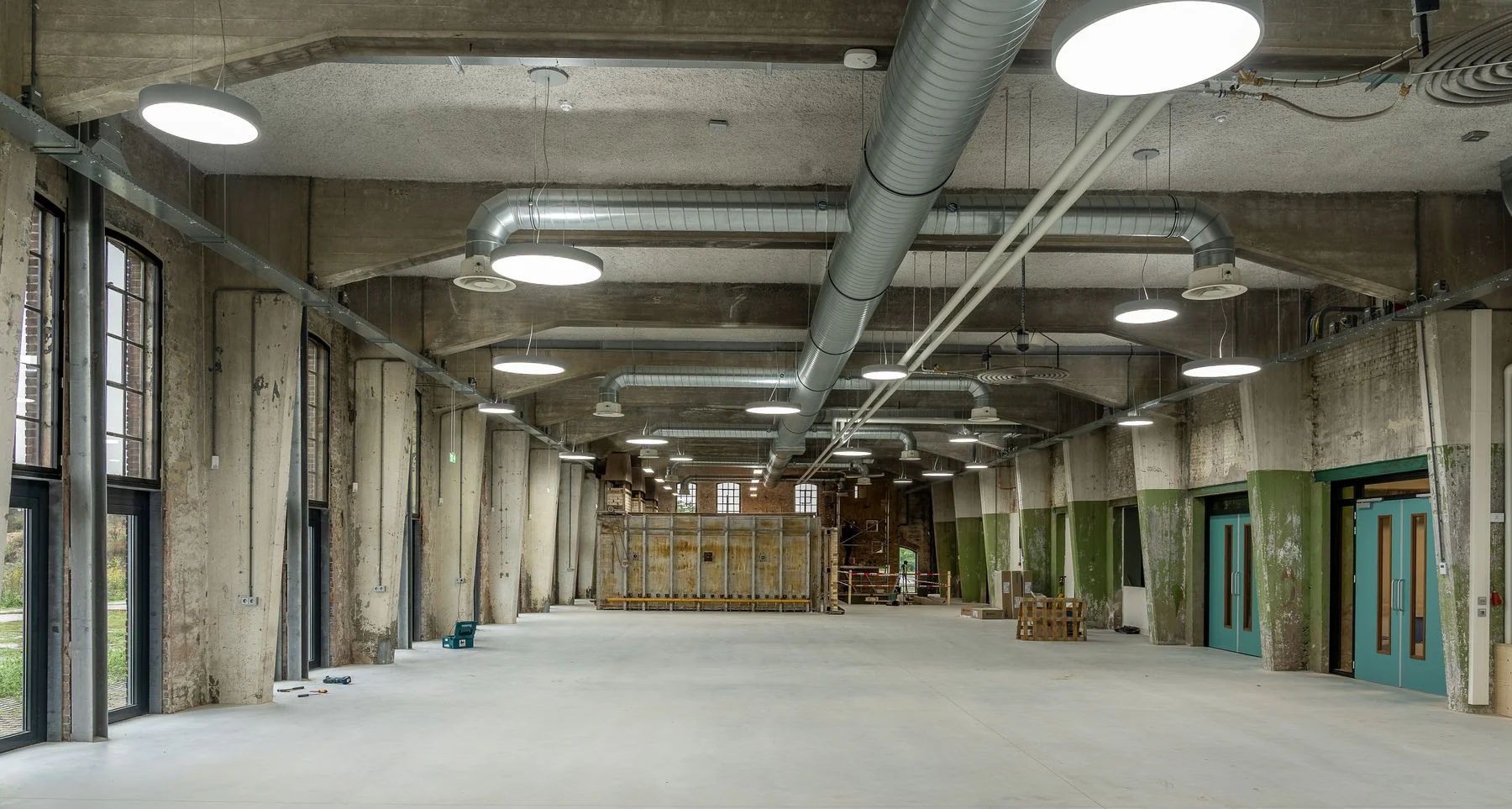 Large empty industrial interior with exposed ducts and concrete surfaces