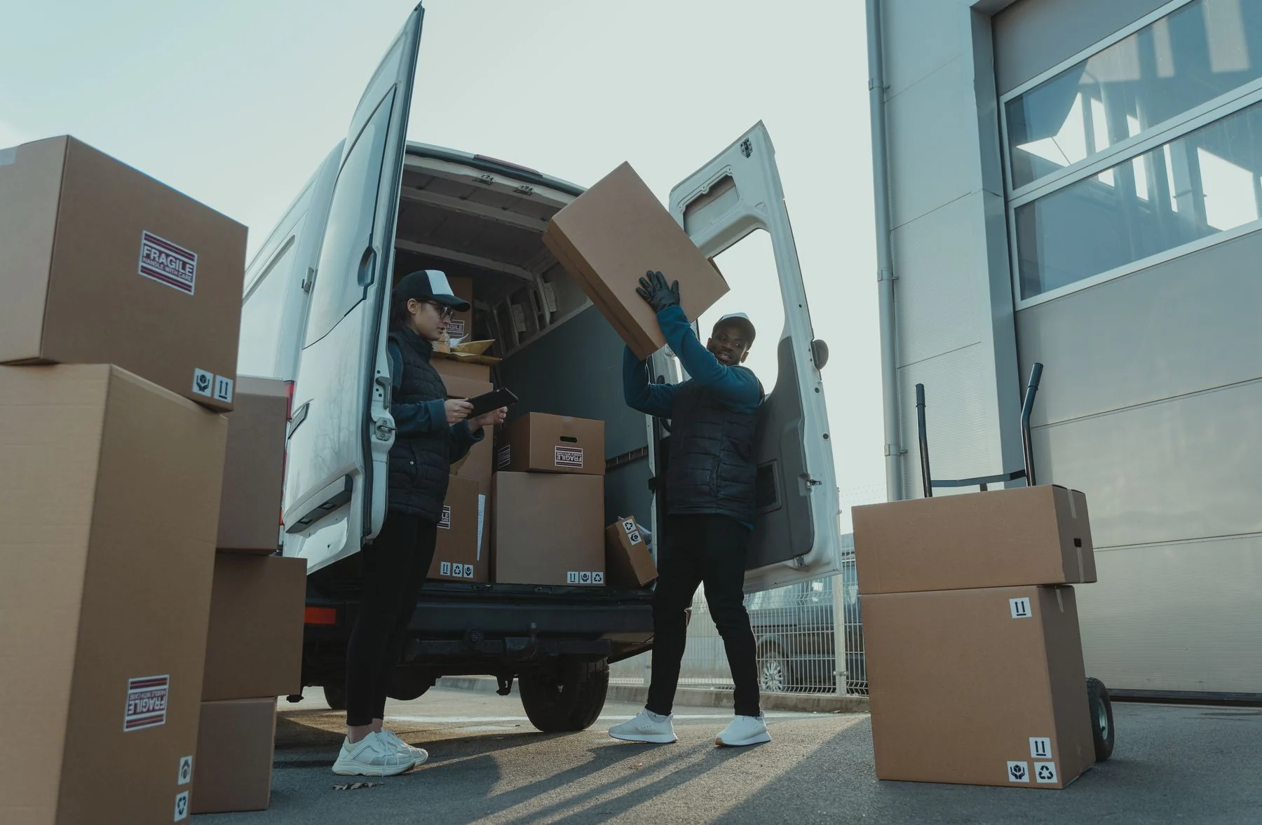 Two workers loading boxed cargo into a van