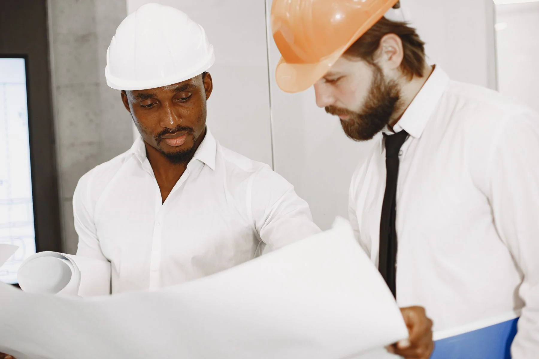 Two people reviewing large drawings indoors