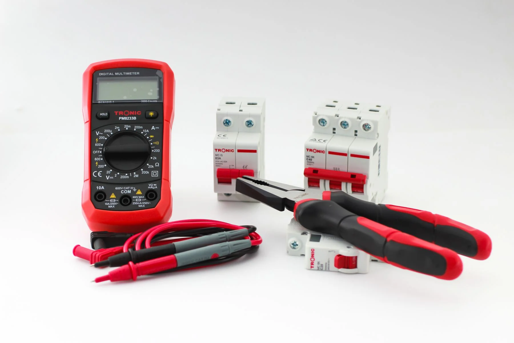 Multimeter, circuit breakers, screwdrivers and pliers on a white surface