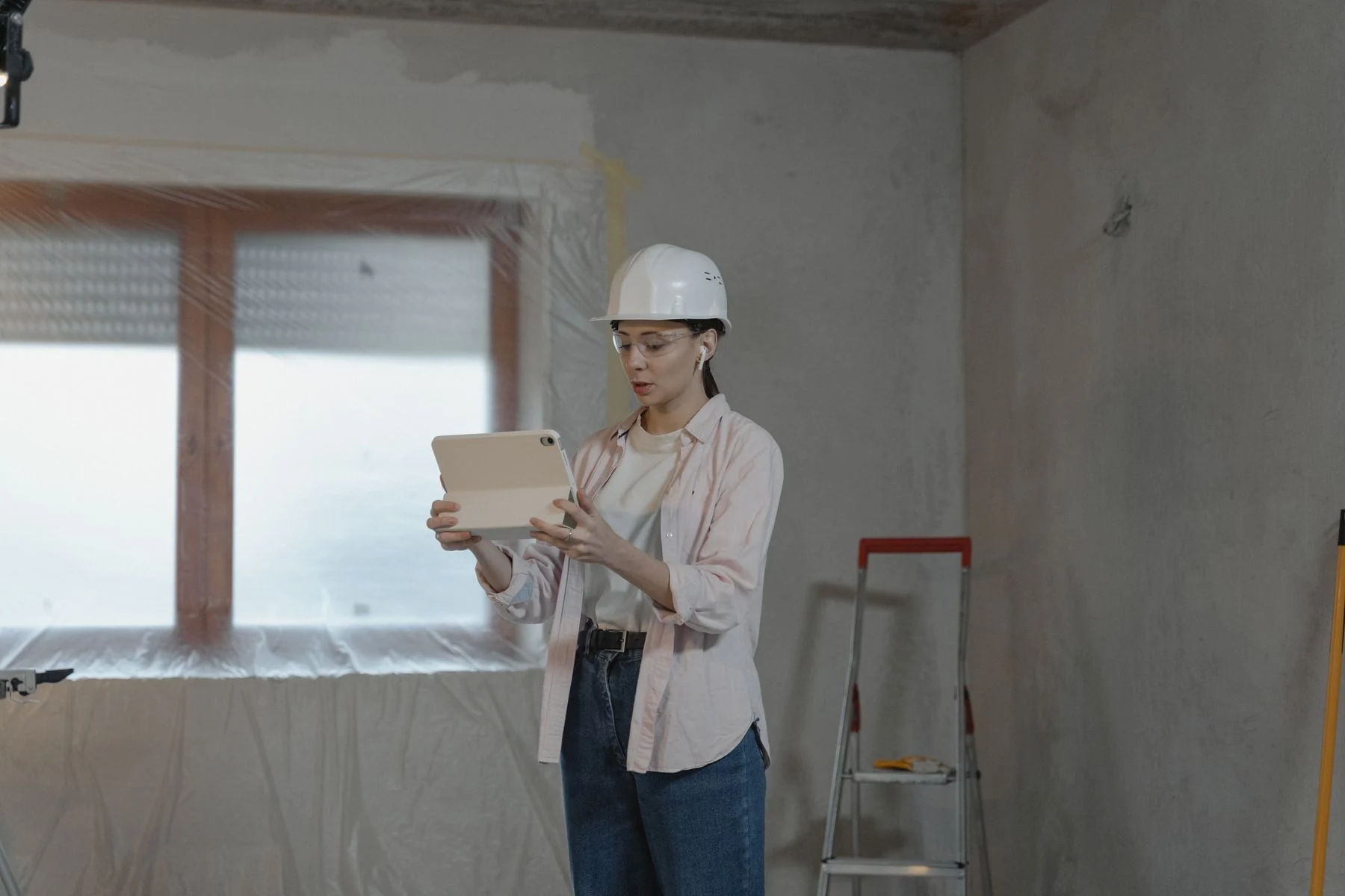 Worker wearing a hardhat using a tablet in unfinished interior