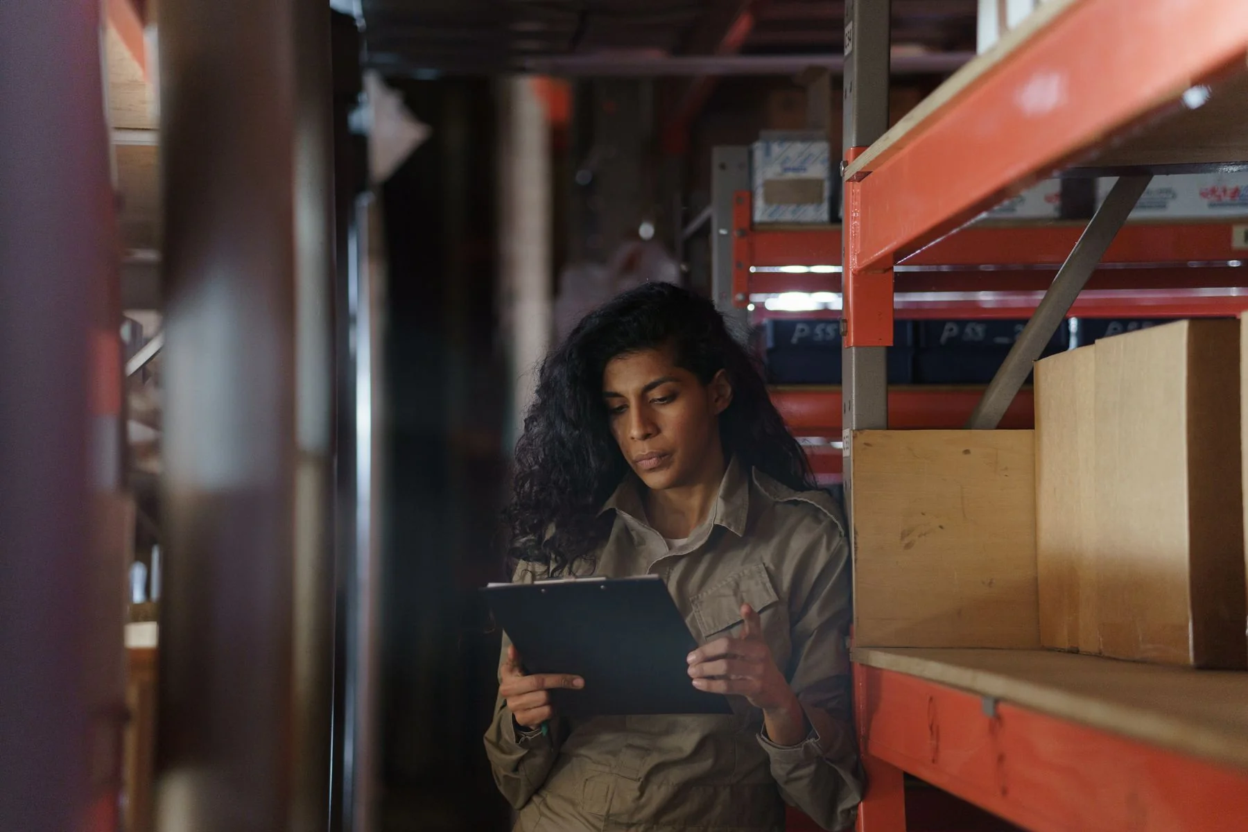 Person reviewing documents beside workshop storage shelves