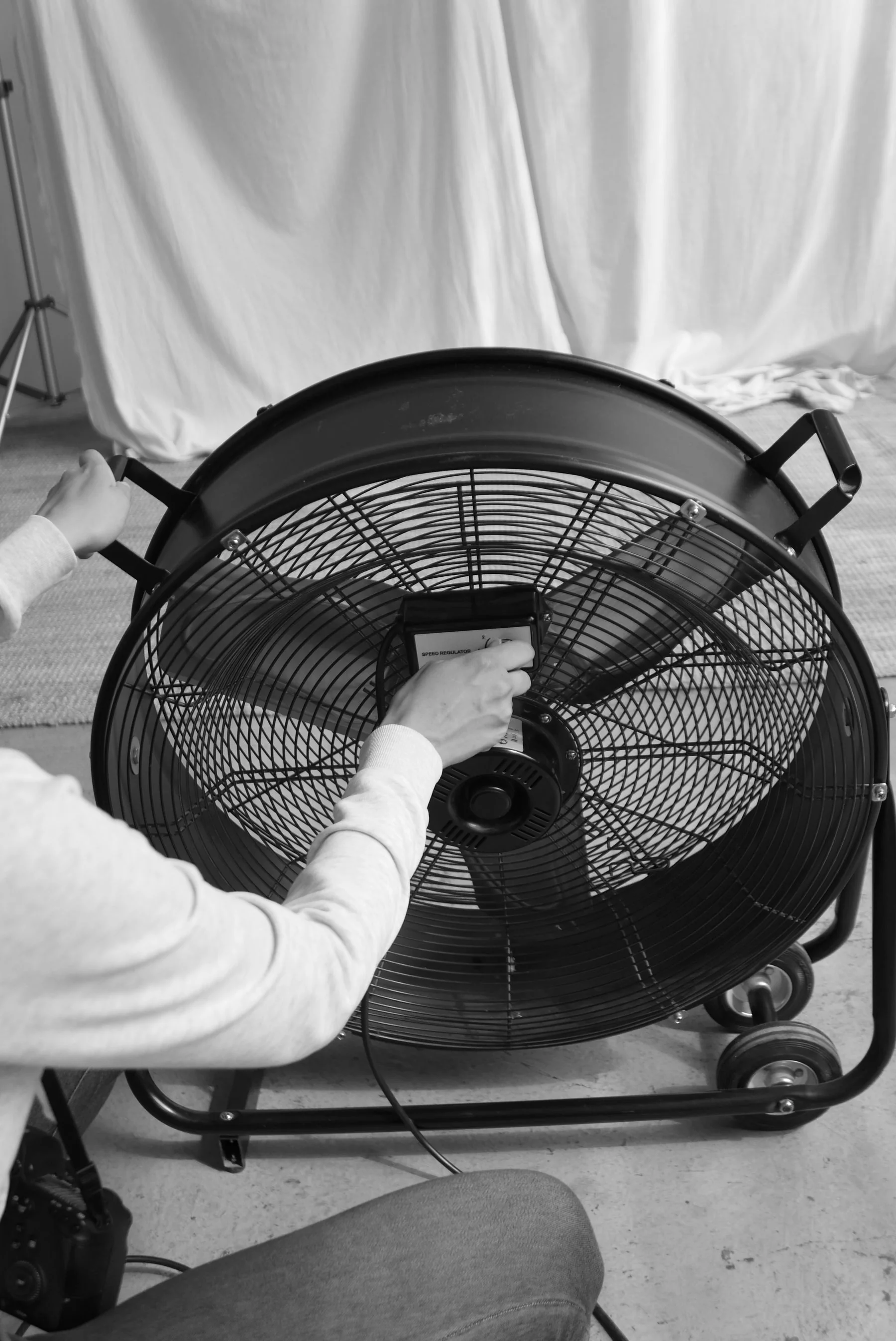 Large wheeled industrial fan being adjusted indoors