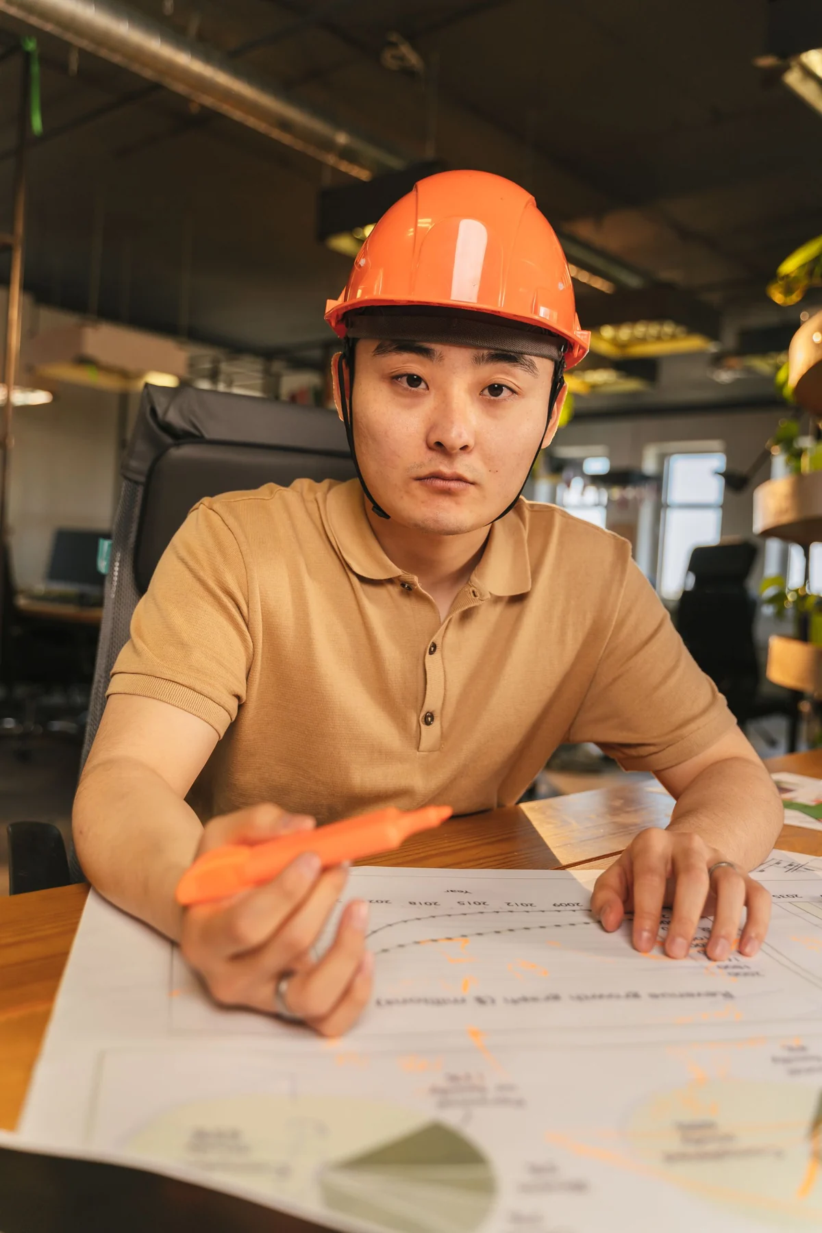 Hardhat-wearing worker reviewing drawings at a desk