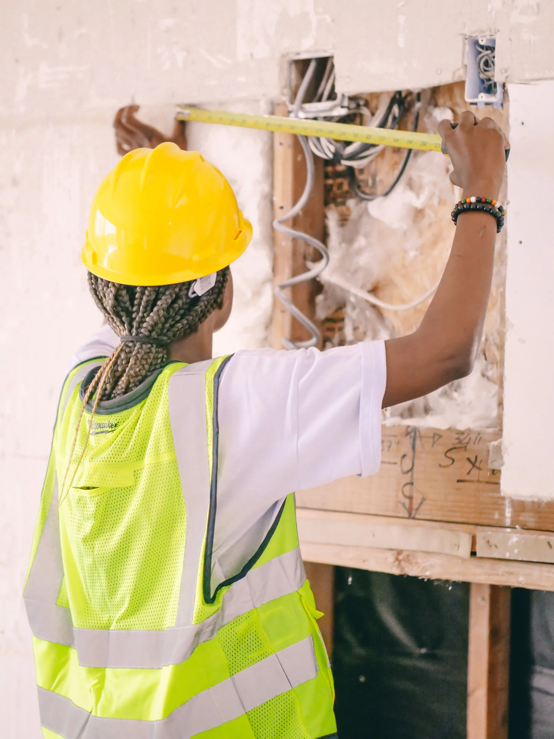 Worker using a measuring tape at an unfinished wall