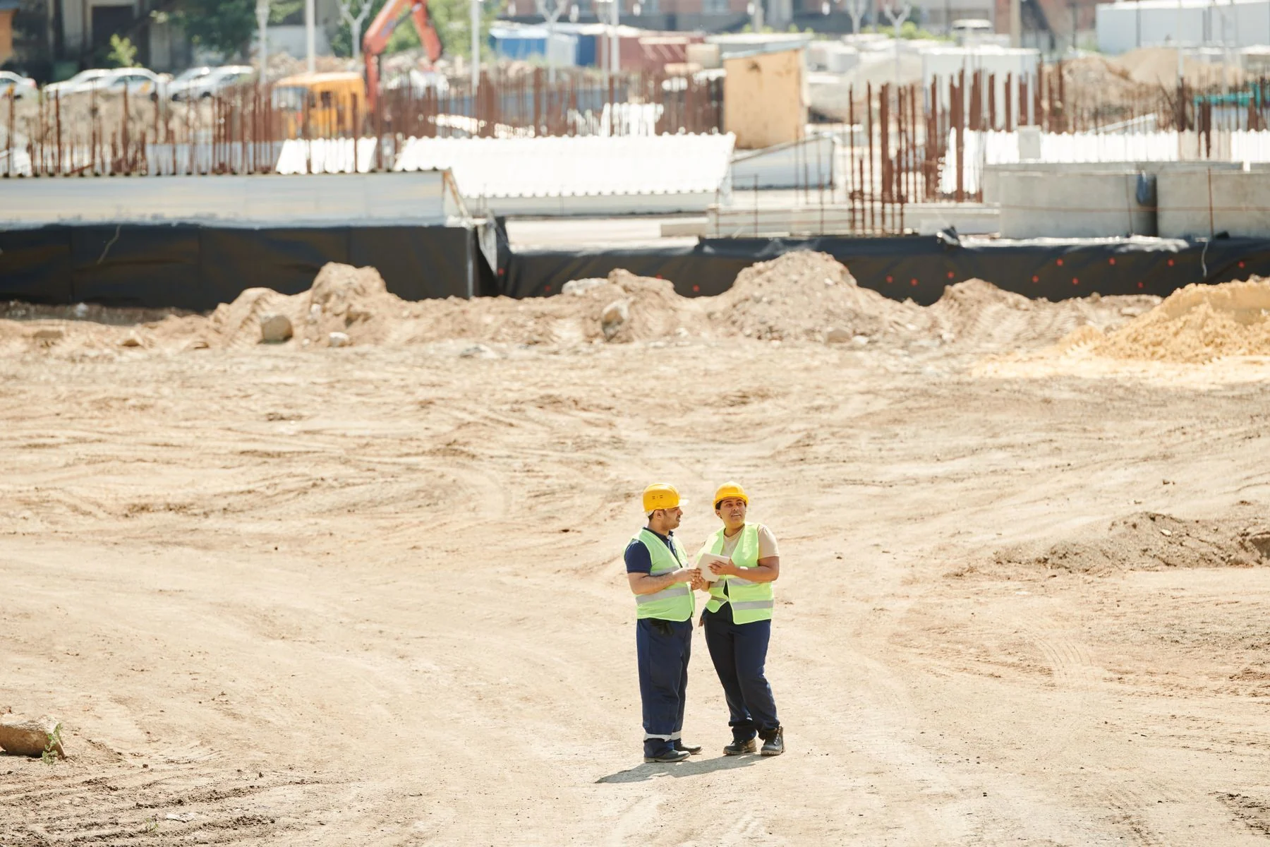 Two workers discussing a broad construction site outdoors