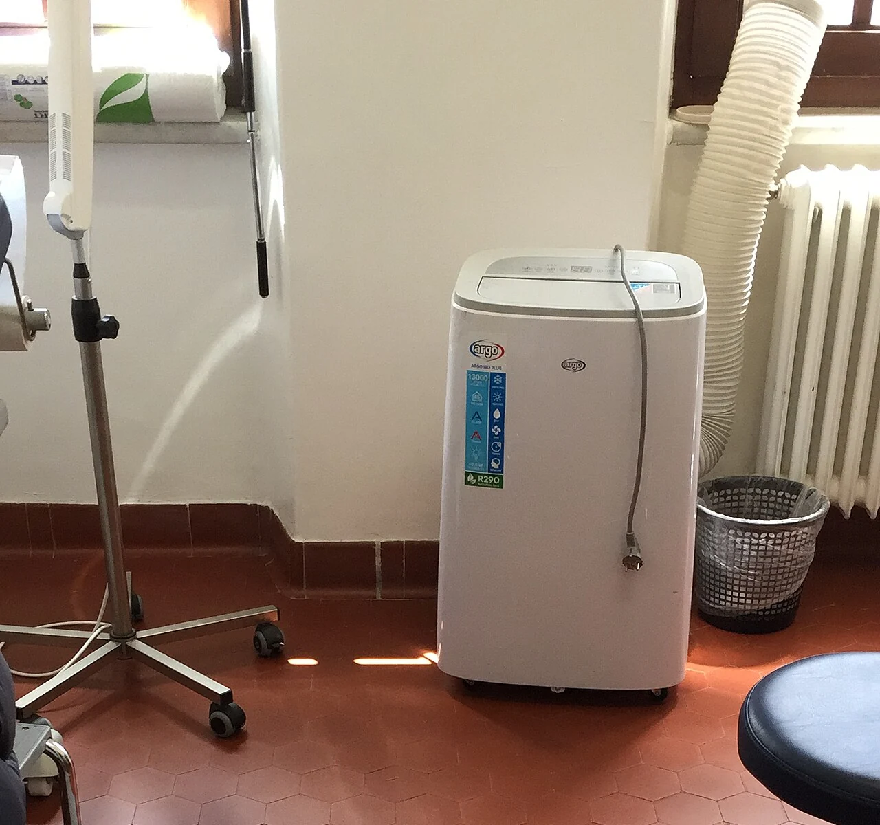 Portable air conditioner with flexible exhaust duct in an indoor room