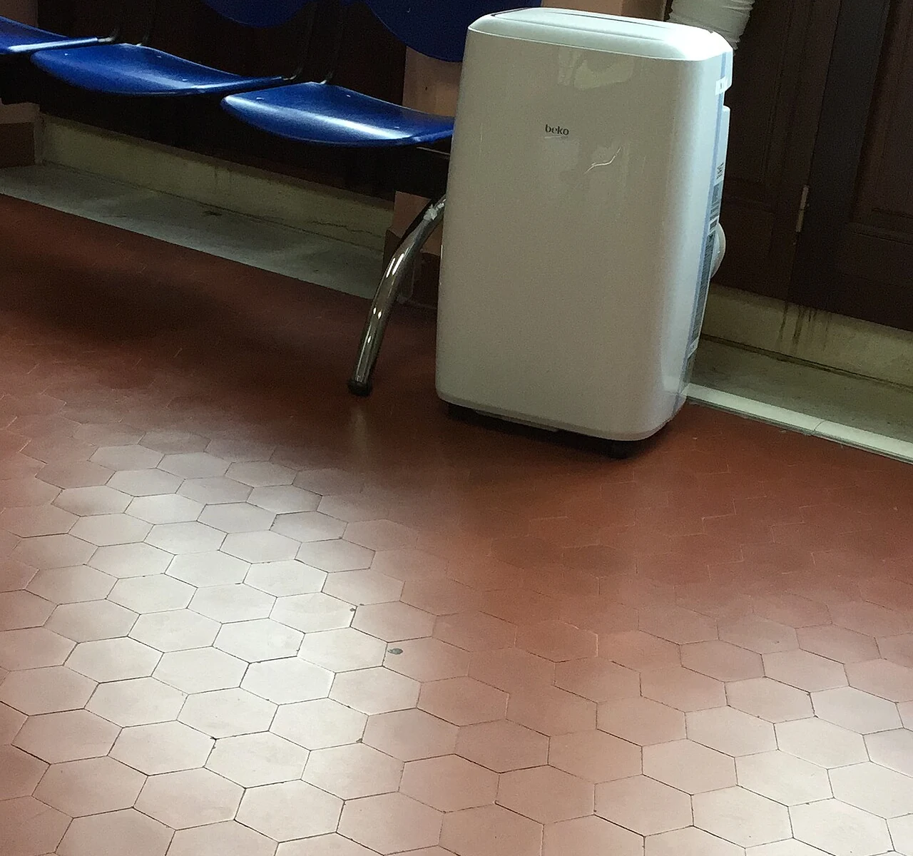 Portable air conditioner beside seating with exhaust duct